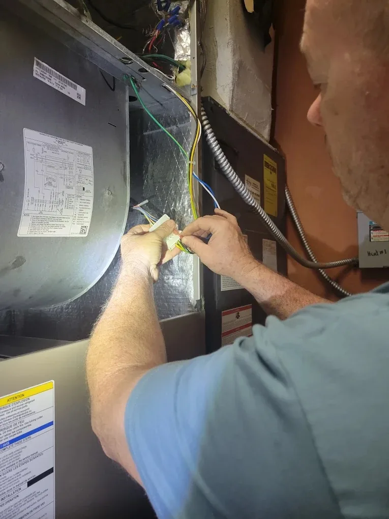 Coolmore technician servicing electrical wiring inside an indoor air handler