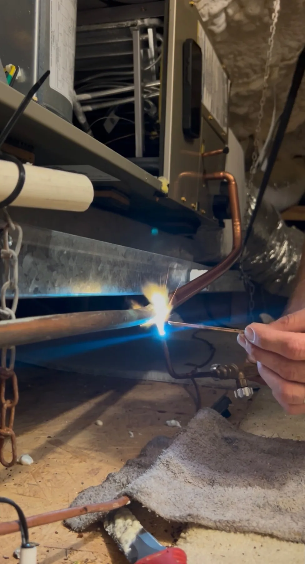 HVAC technician brazing a copper refrigerant line during AC repair