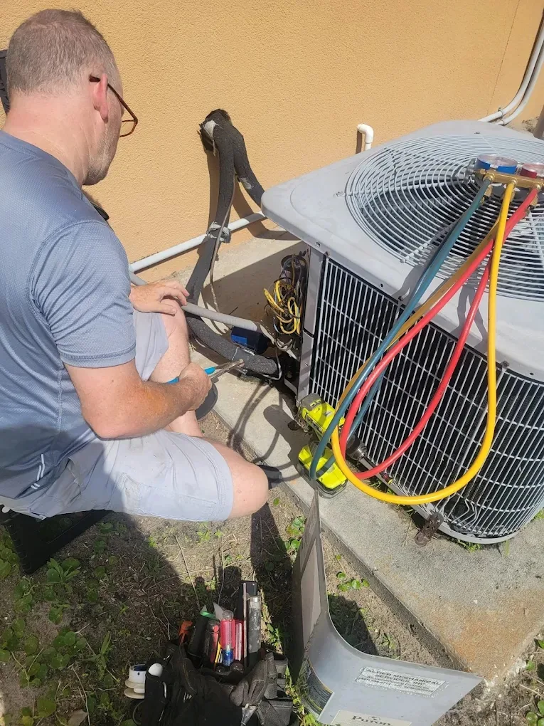 Technician checking outdoor AC condenser with gauges