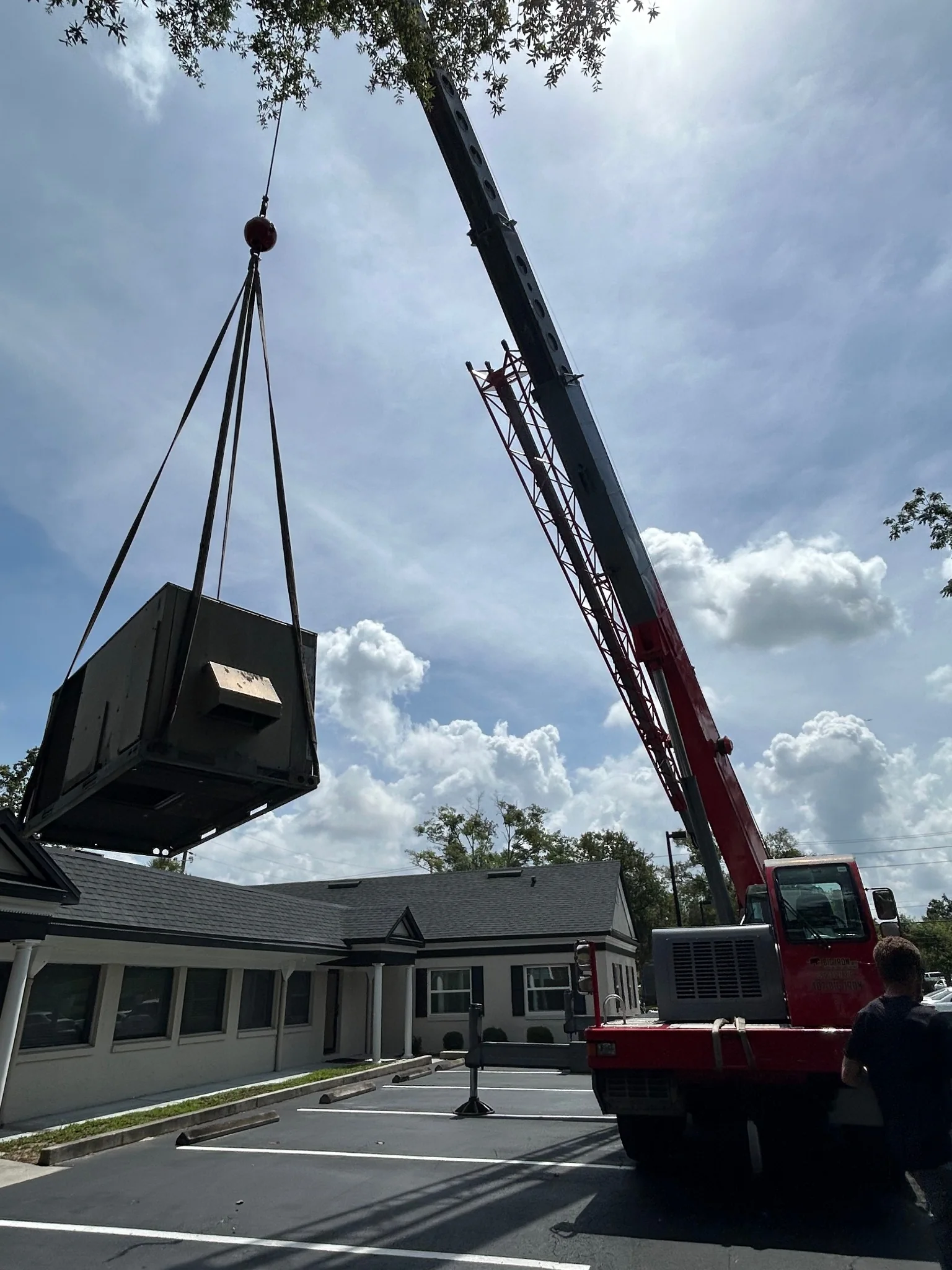 Crane lifting commercial HVAC equipment for a building project